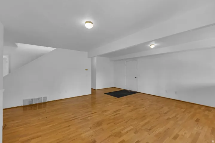 Expansive interior space featuring wood-finish flooring, white walls, and a staircase
