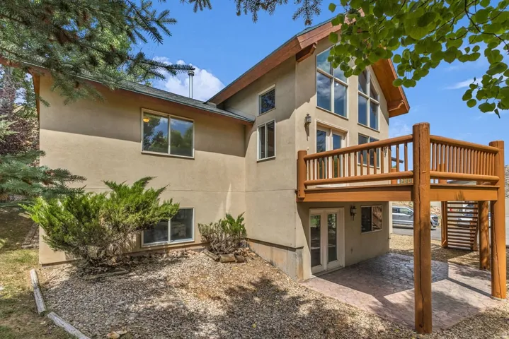 Stucco exterior with a prominent wooden deck featuring log supports