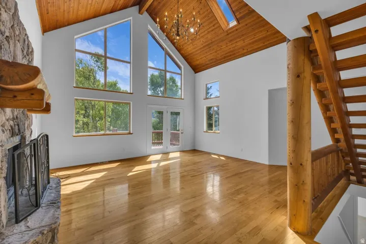 Great room featuring a vaulted wood-finish ceiling, exposed log beam, and hardwood flooring