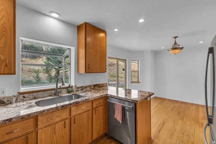 Kitchen featuring a stainless steel undermount sink, granite countertops, and light wood cabinetry