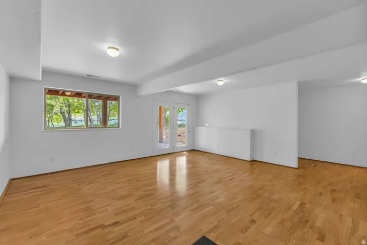 Spacious room featuring wood-finish flooring, white walls, and recessed lighting