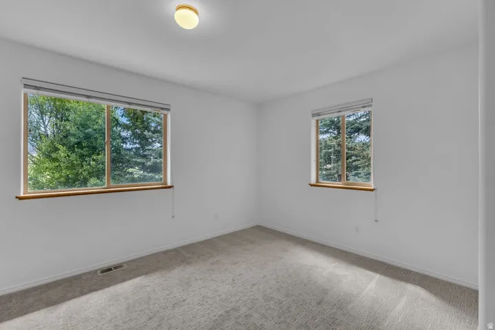 Bright room featuring two windows with wood sills and exterior tree scenery