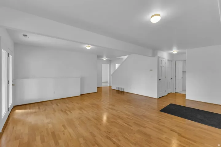 Spacious room featuring wood-finish flooring, white walls, and contemporary flush-mount lighting