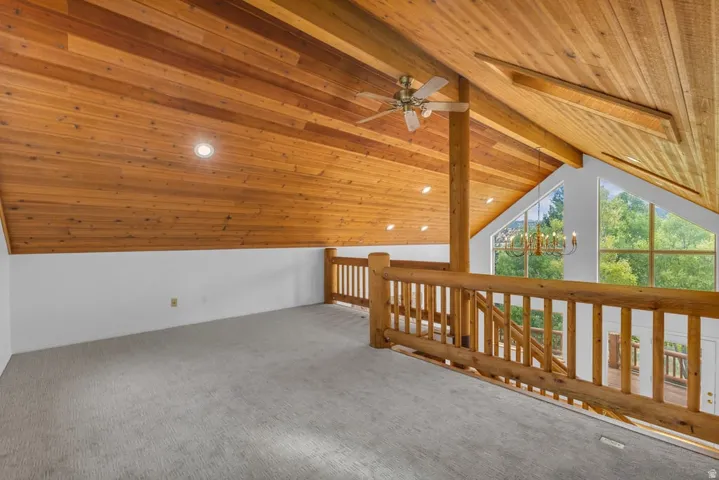 Expansive loft space featuring wood-paneled vaulted ceilings with recessed lighting and a ceiling fan