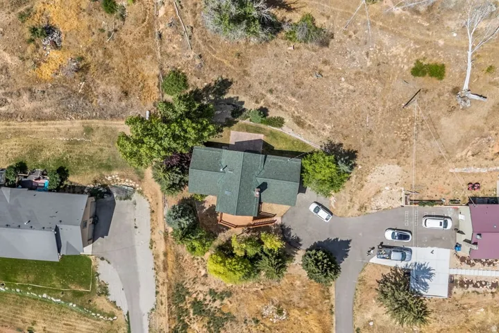 Property with a green-shingled roof, a substantial wooden deck, and mature trees