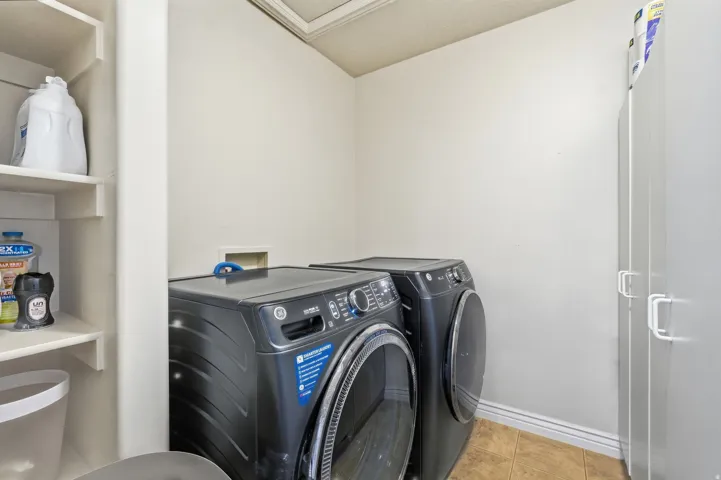 Spacious laundry room with shelving located upstairs