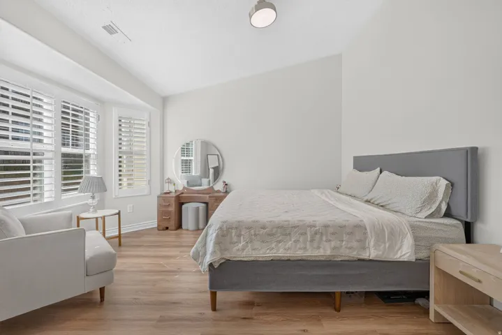 Primary Suite featuring new flooring, fresh paint,  plantation shutters, and vaulted ceilings