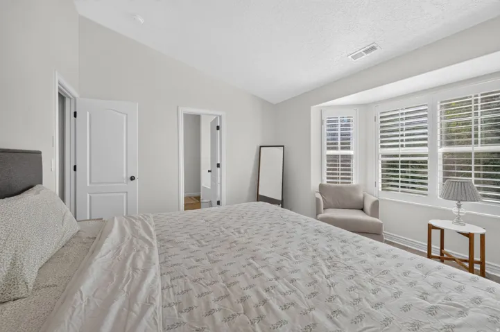 Vaulted ceiling room featuring a bay window with plantation shutters