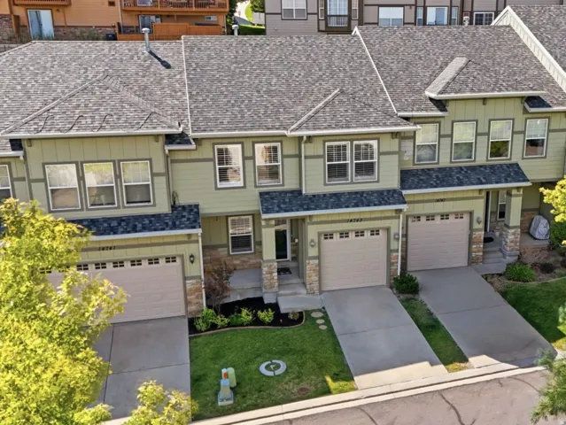 Townhome exterior featuring light green siding, stone accents, and dark gray shingle roofing