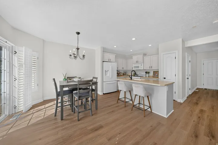 Open-concept kitchen and dining area featuring new LVP flooring, white cabinetry, recessed lighting, and a kitchen island with seating