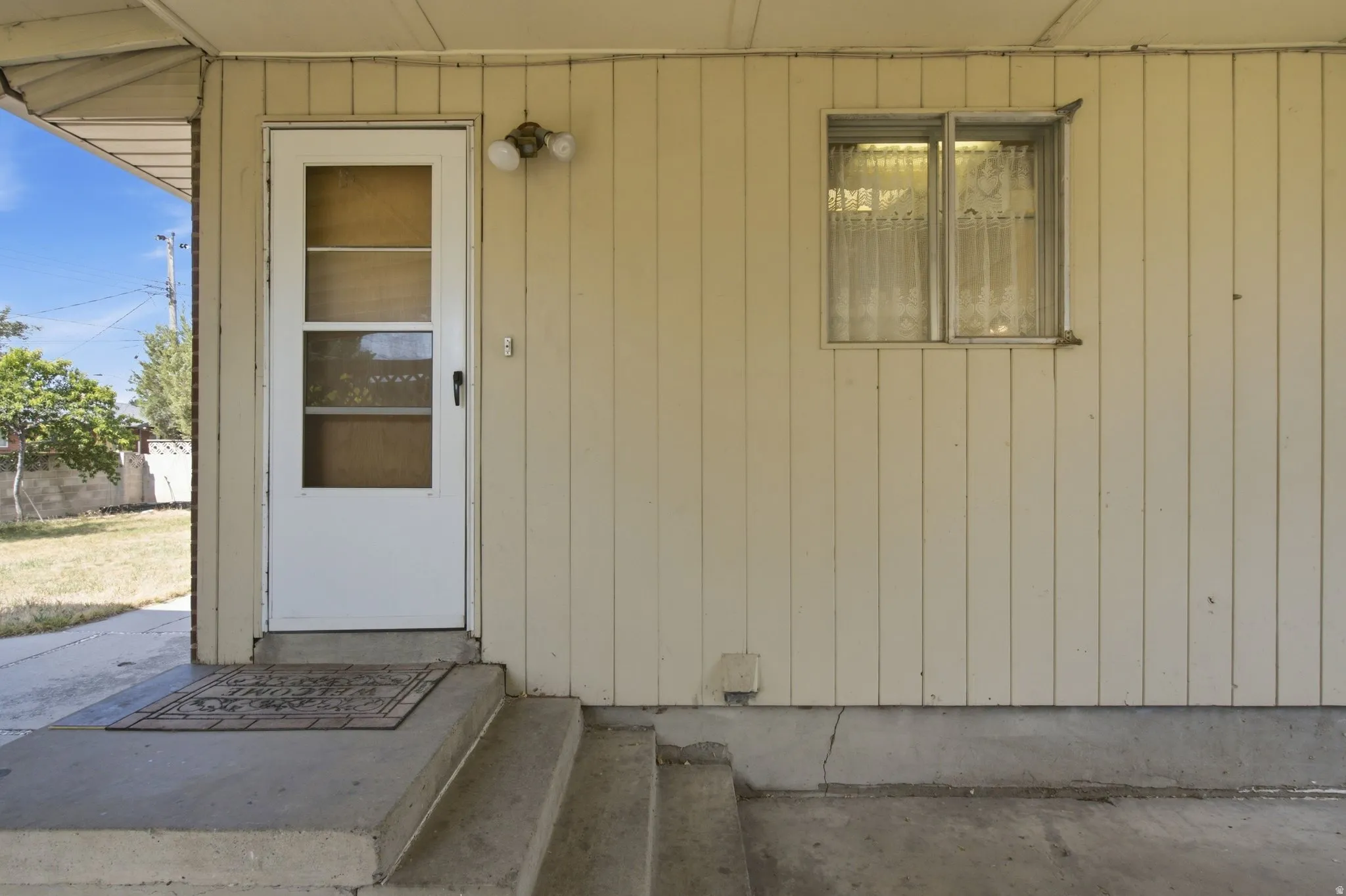 Covered entry with concrete steps and a screen door