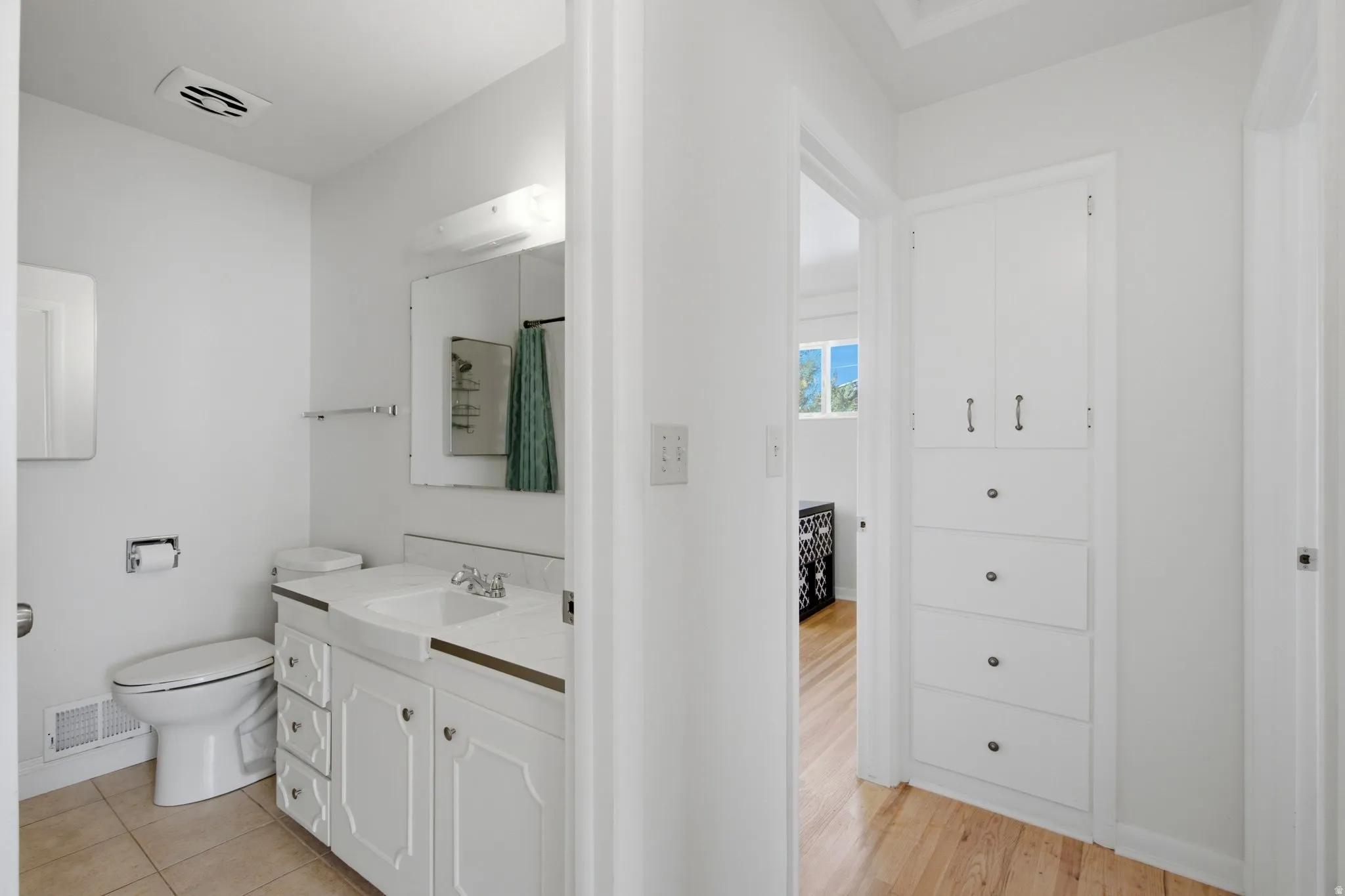 Bathroom featuring a white vanity with integrated sink, a wall-mounted mirror, and tile flooring