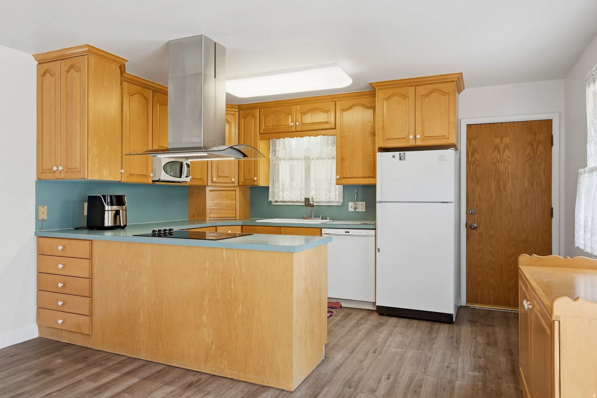 Kitchen featuring wood cabinetry, light blue countertops, and wood-finish flooring
