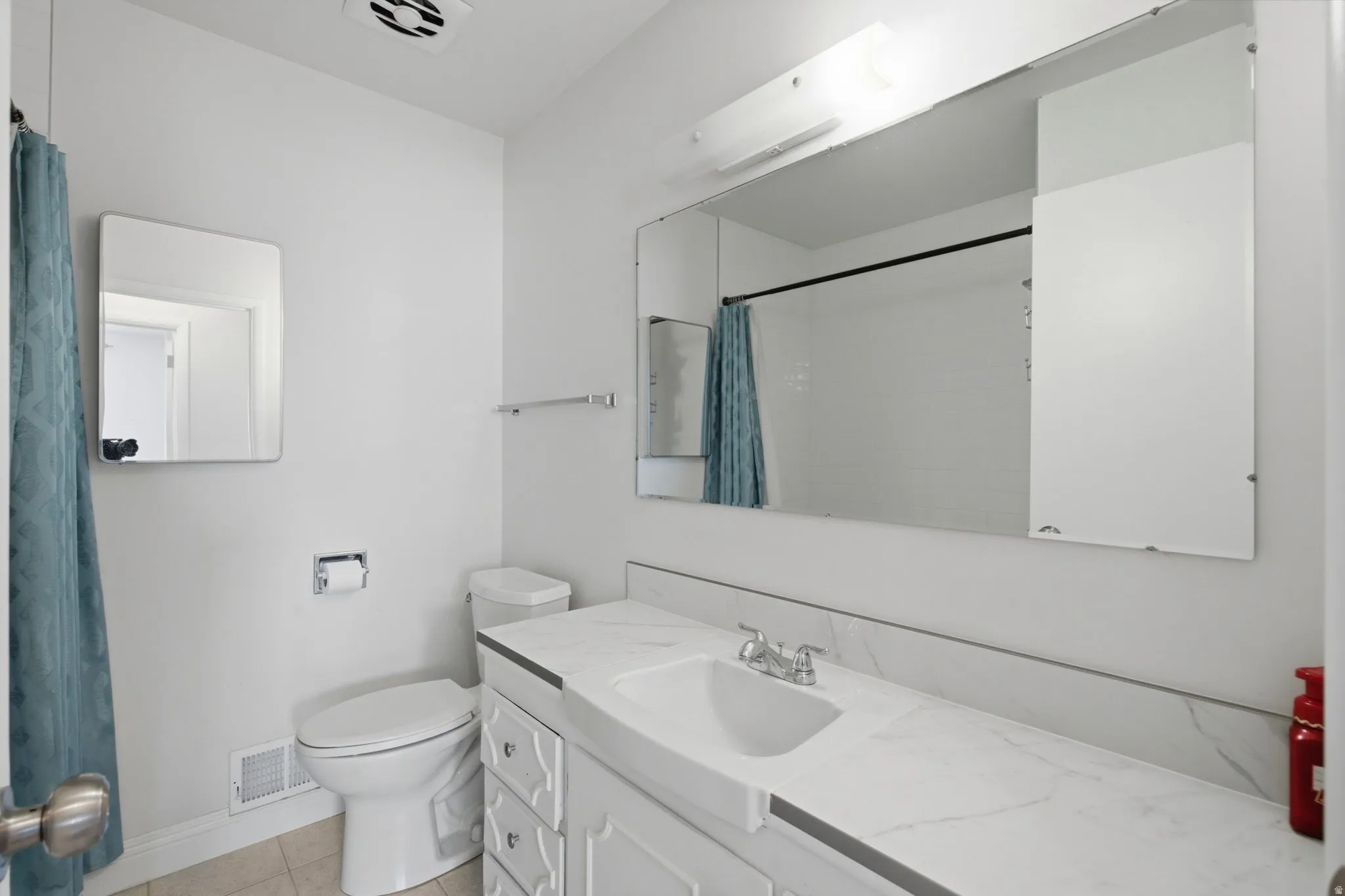 White vanity with integrated sink, chrome faucet, and expansive wall-mounted mirror