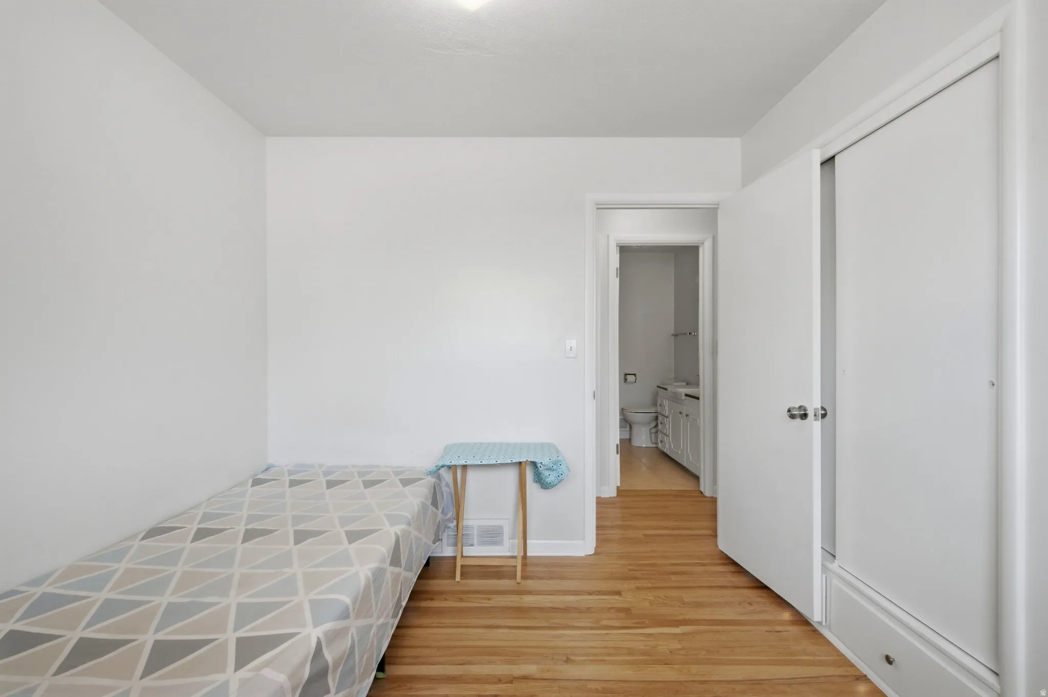 Hardwood flooring throughout, white walls, and a recessed ceiling light