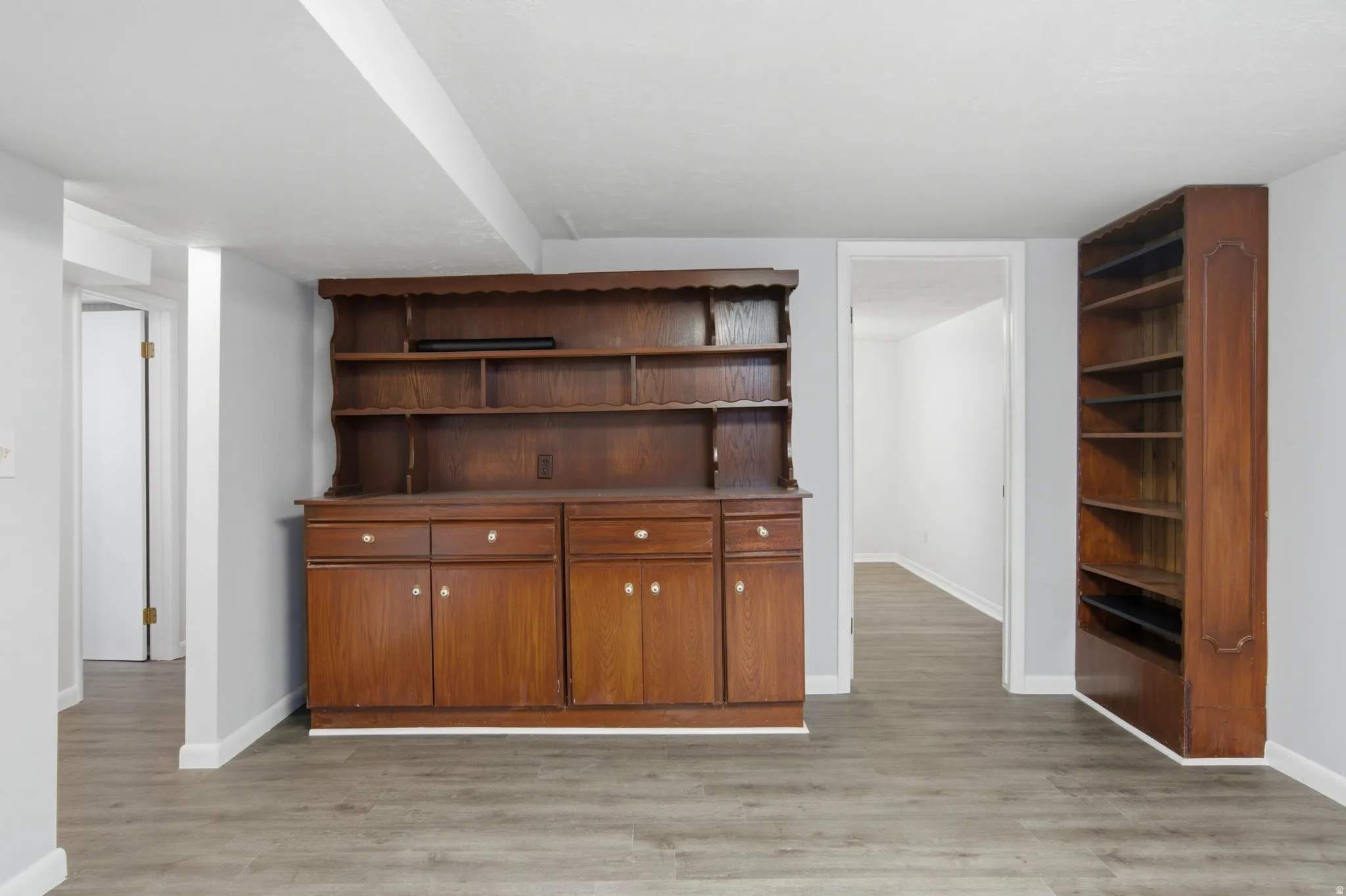 Spacious room with wood-finish flooring, light grey walls, and a white ceiling