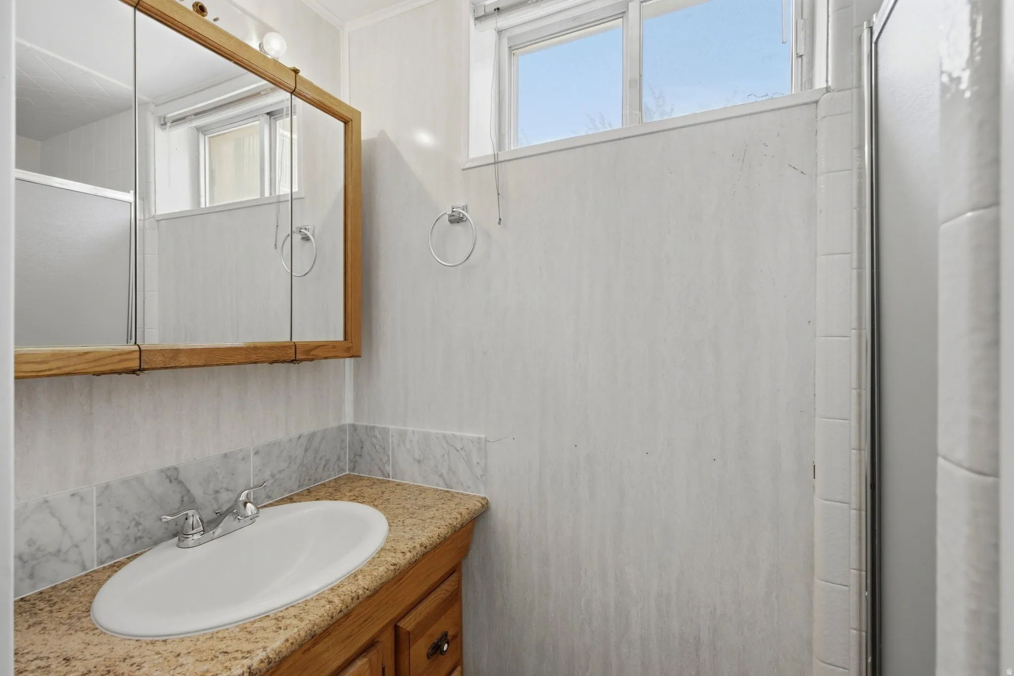 Bathroom vanity featuring an oval undermount sink with a chrome faucet