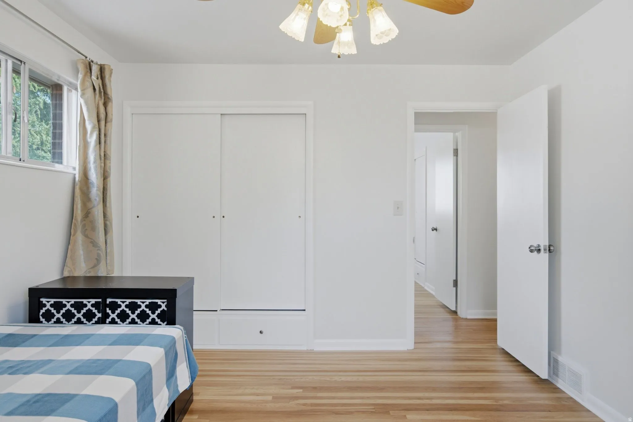 Room featuring wood-finish flooring, a window with exterior views, and a ceiling fan with integrated lighting