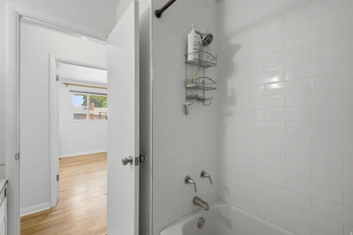 White subway tile surrounds the shower/tub combination with chrome fixtures