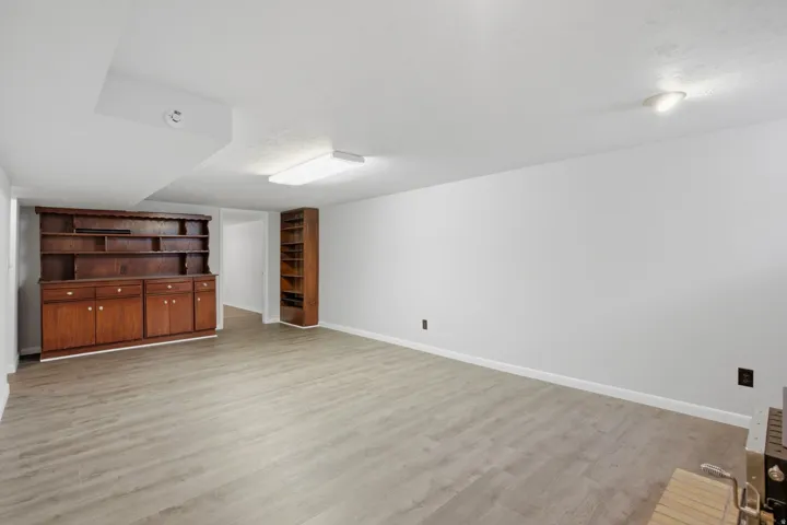 Spacious room featuring wood-finish flooring, a built-in wooden hutch with shelving and cabinetry, and an additional built-in wooden bookshelf