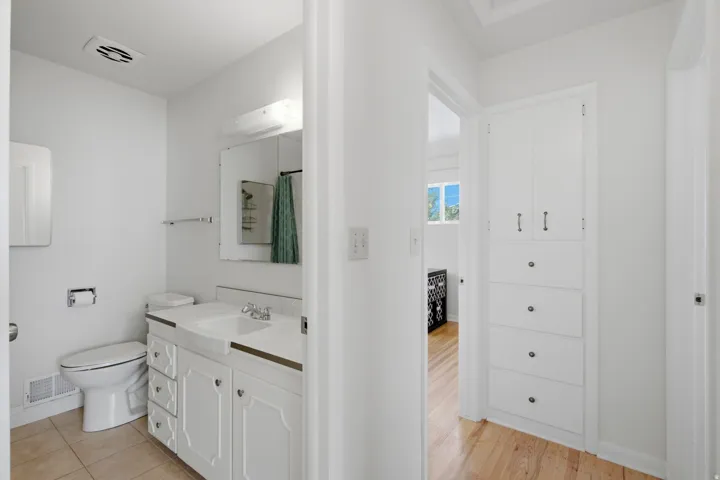 Bathroom featuring a white vanity with integrated sink, a wall-mounted mirror, and tile flooring