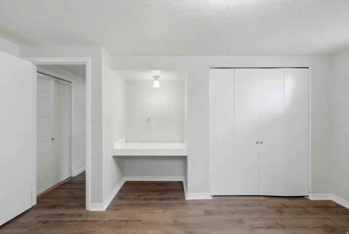 Interior room featuring wood-finish flooring, a built-in desk with task lighting, and bi-fold closet doors