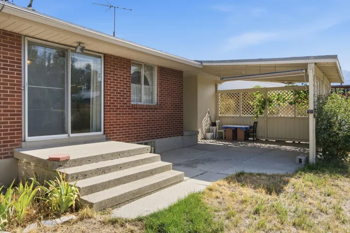 Brick exterior featuring a concrete patio with a covered section and lattice privacy screening
