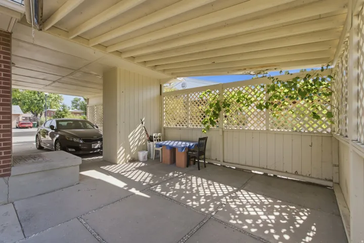 Covered concrete patio area with a slatted ceiling and lattice privacy screening