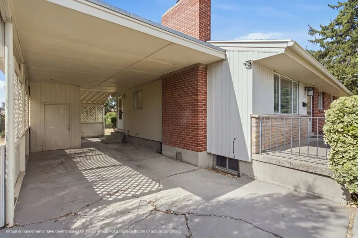 Covered carport area featuring a concrete drive, side entry door, and lattice details