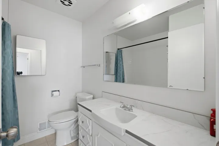 White vanity with integrated sink, chrome faucet, and expansive wall-mounted mirror