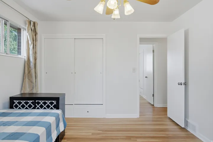 Room featuring wood-finish flooring, a window with exterior views, and a ceiling fan with integrated lighting