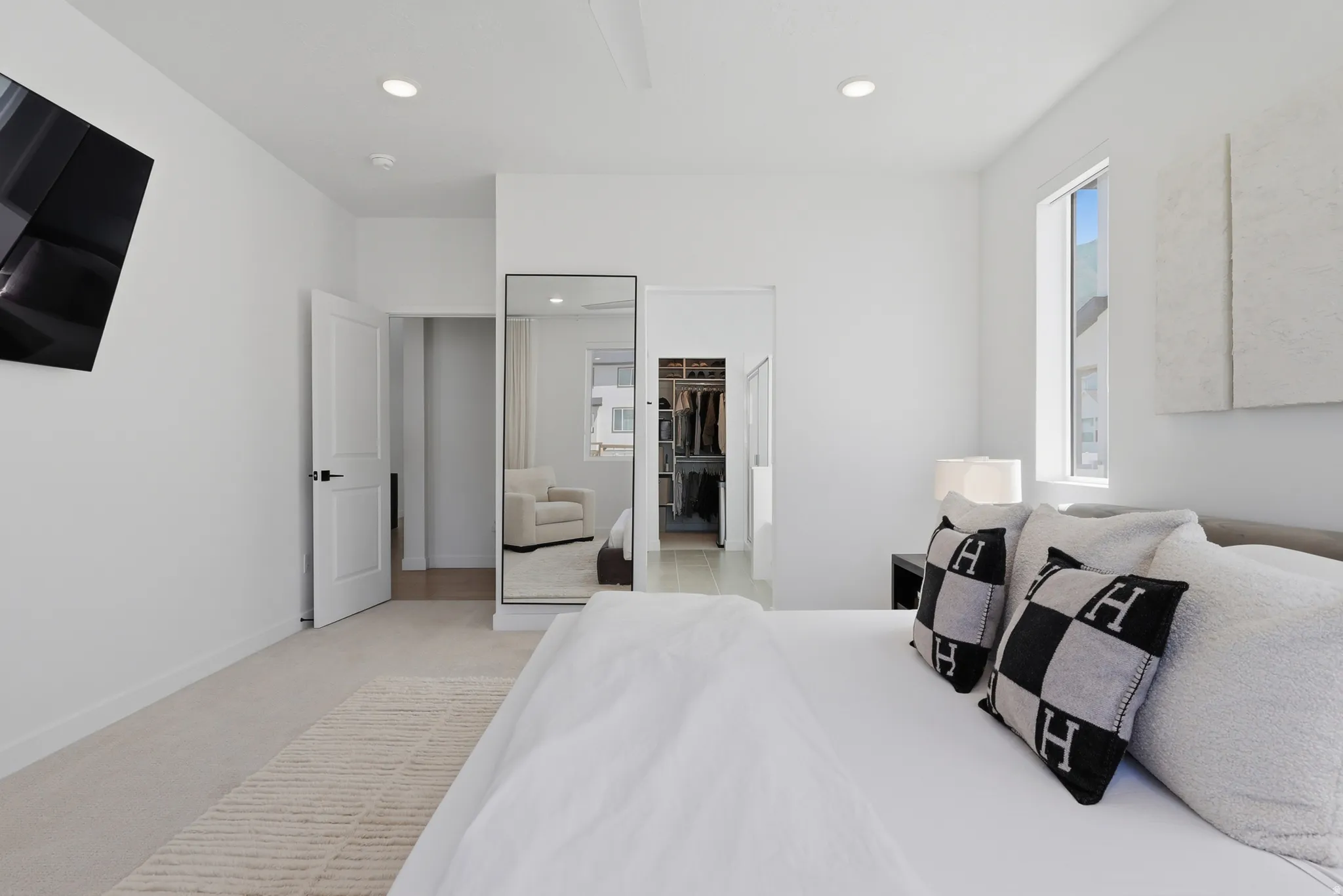 Bright bedroom featuring recessed lighting, a ceiling fan, plush carpeting, a tall window, and a walk-in closet with built-in shelving