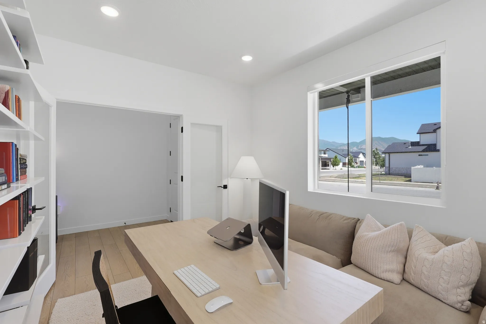 Bright interior room featuring a large window, built-in shelving, recessed lighting, wood-finish flooring, and a wide entryway