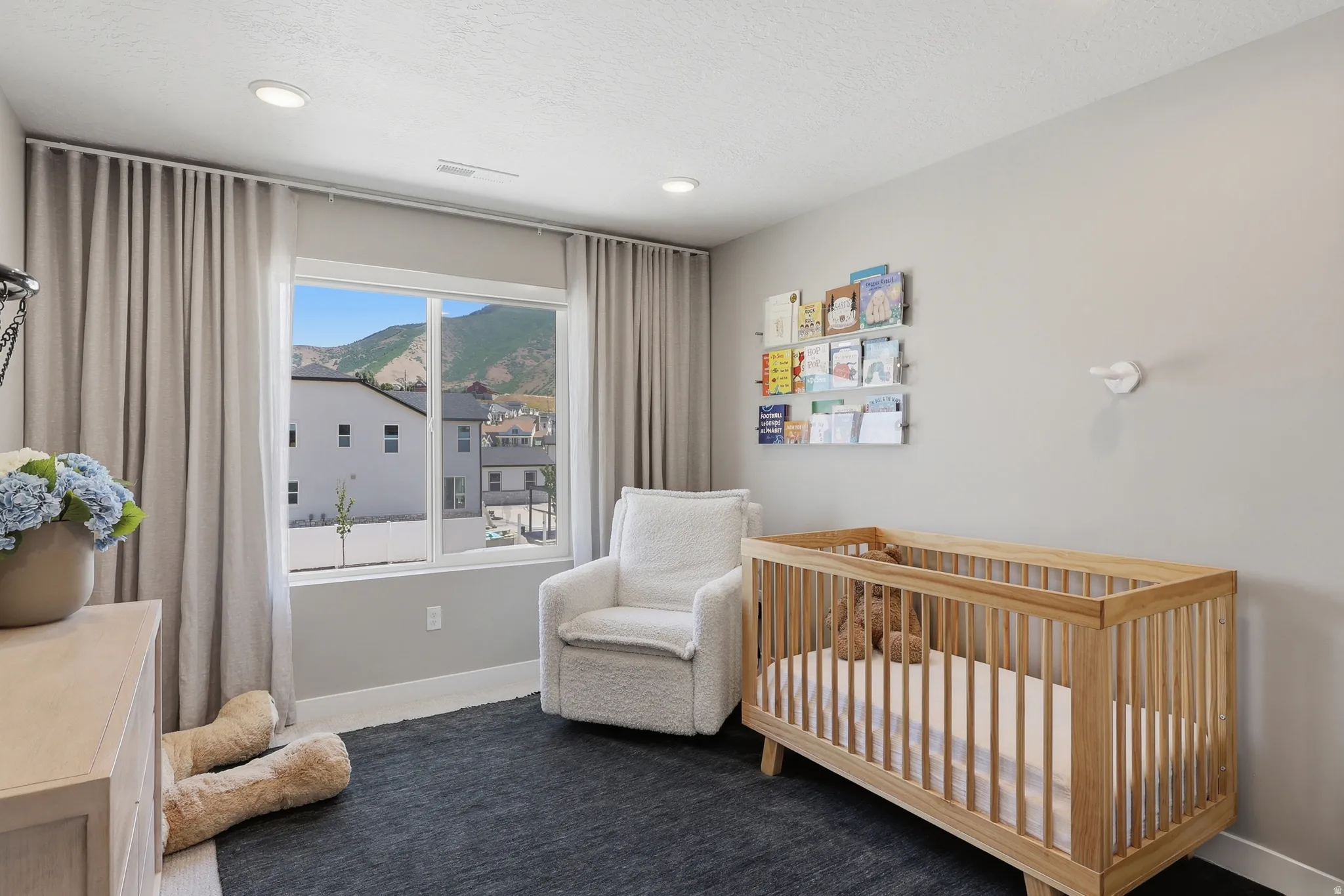 Large window with mountain scenery, recessed lighting, neutral wall paint, light wood-finish flooring, and a dark area rug