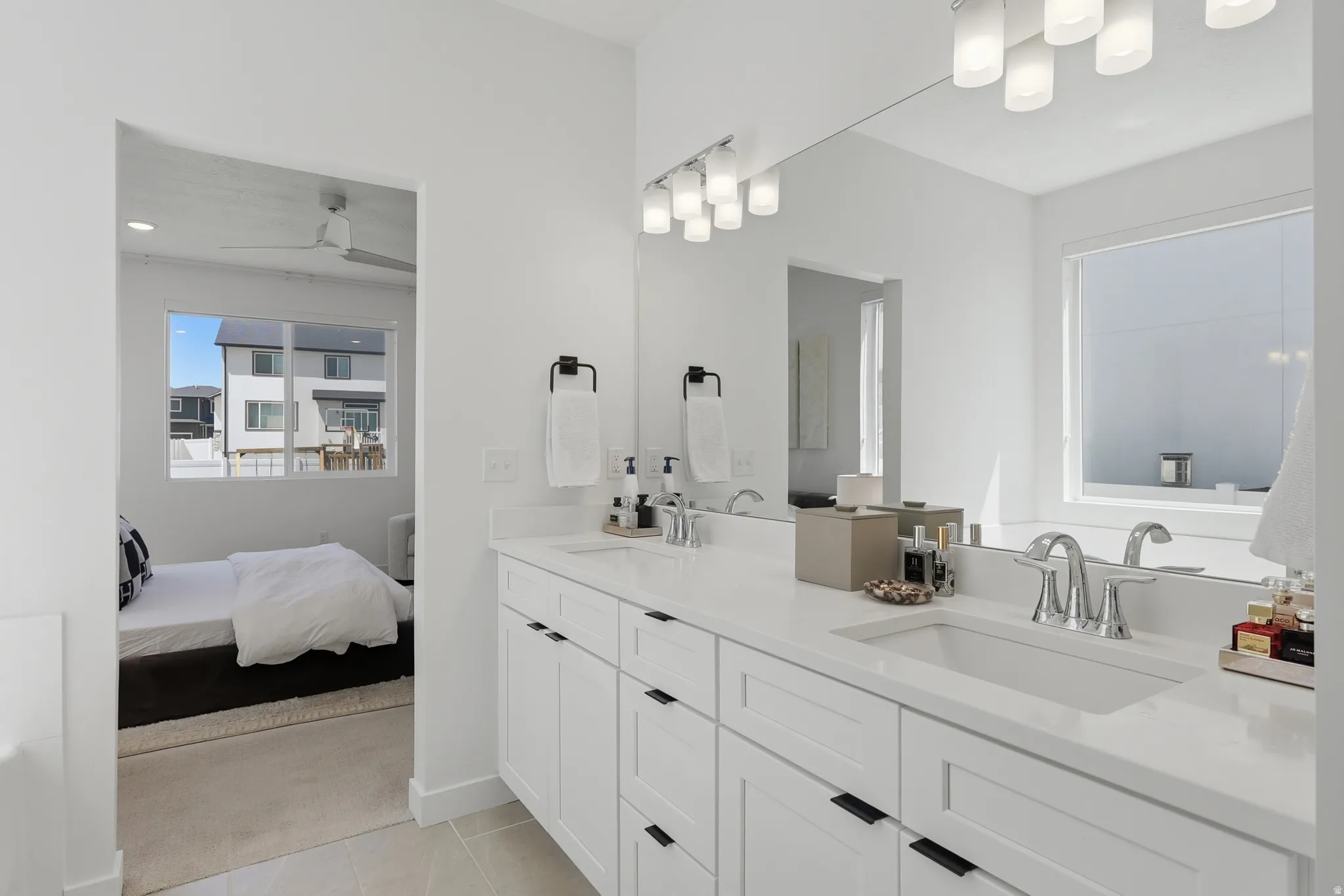 Double vanity with white cabinetry, matte black hardware, and an integrated sink with a chrome faucet