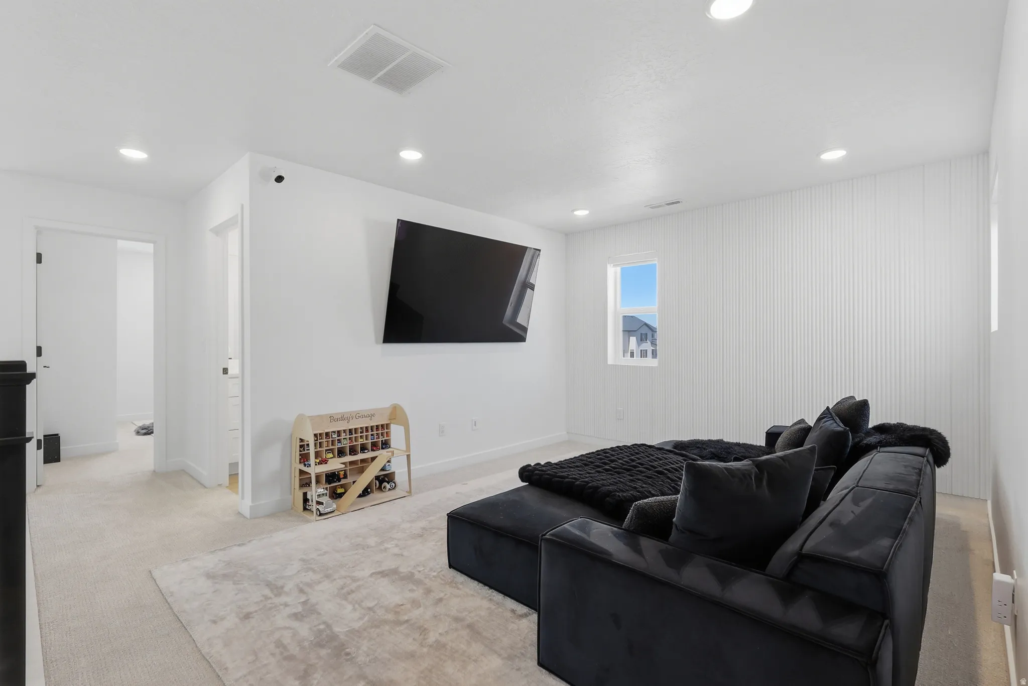 Contemporary interior with recessed lighting, light-toned carpet, and a large wall-mounted display