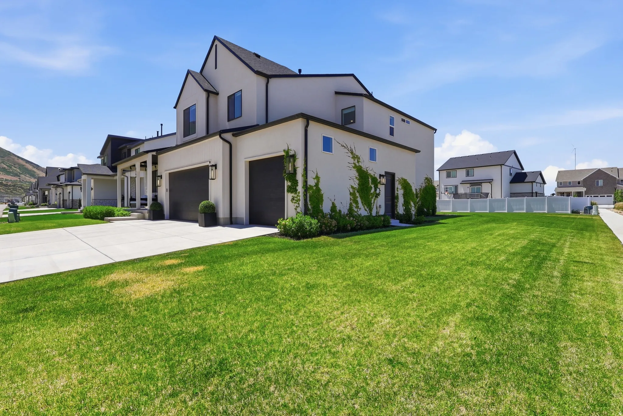 Contemporary residence featuring a light-toned stucco exterior with dark trim and a dark roof