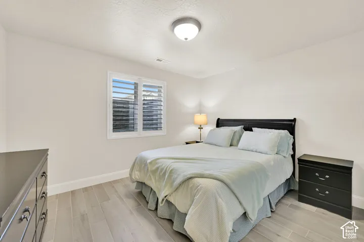Room featuring light wood-finish flooring and a window with white louvered shutters