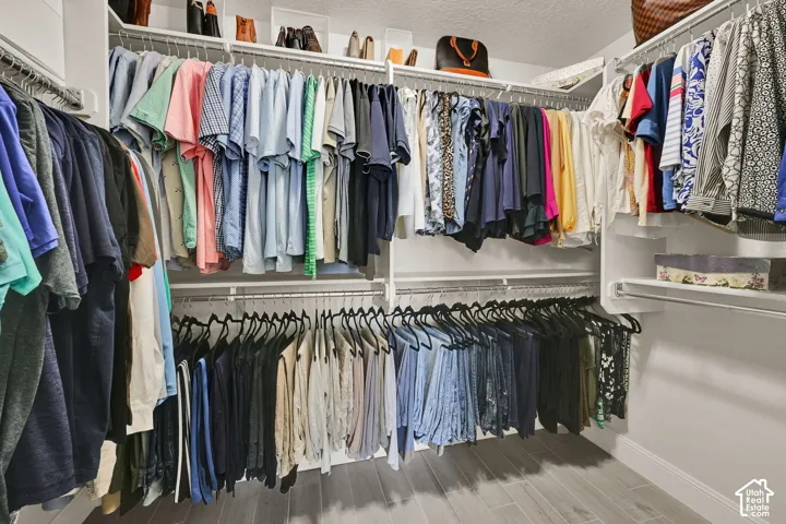 Custom closet system featuring multiple hanging rods, integrated shelving, and wood-finish flooring