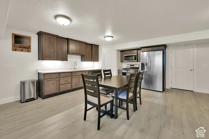 Spacious kitchen area featuring warm wood cabinetry, stainless steel appliances, light-toned countertops, and wood-finish flooring