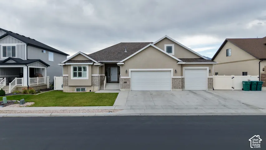 Single-story residence featuring a stucco exterior with brick accents, an integrated two-car garage, and a separate one-car garage