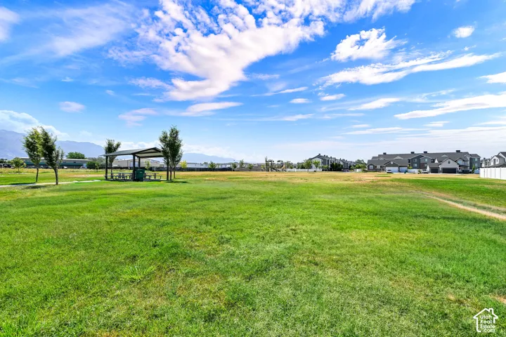 Expansive green space featuring a picnic shelter, scattered trees, and distant mountain ranges