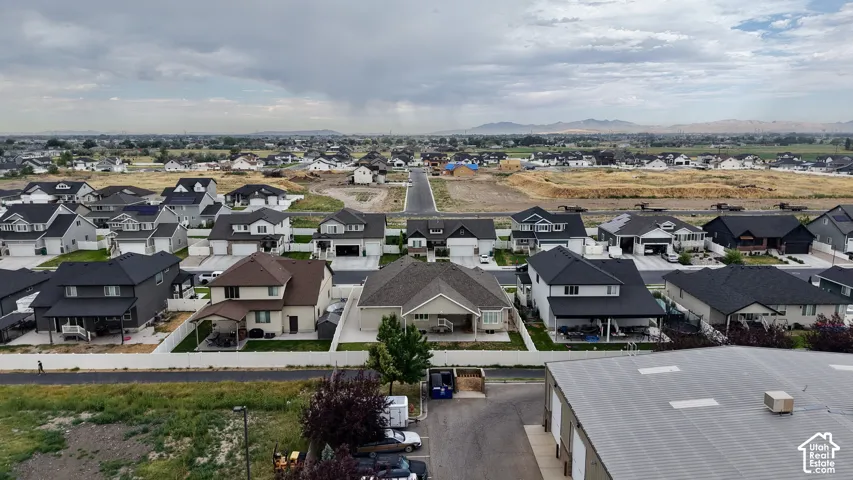 Aerial perspective showcasing a residential development with varied home designs, paved streets, and mountainous terrain in the distance