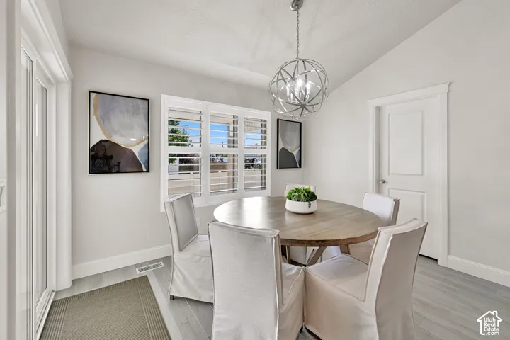 Dining area featuring a contemporary spherical chandelier, vaulted ceiling, and wood-finish flooring