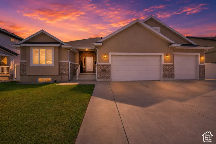 Contemporary stucco and stone-clad exterior featuring a two-car garage, an additional single-car garage, and a concrete driveway