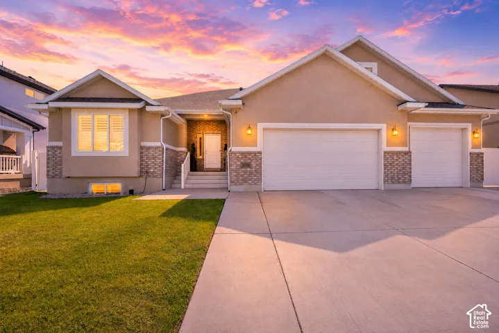Exterior stucco and brick facade featuring a two-car garage, a one-car garage, and a concrete driveway