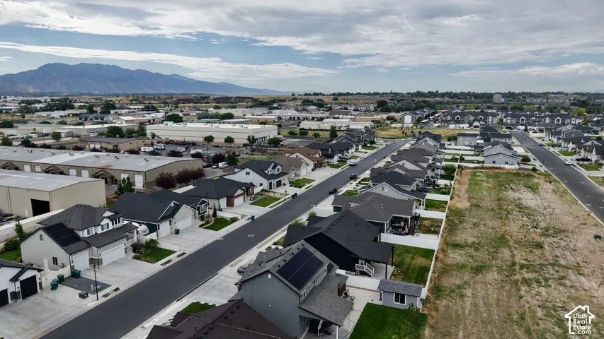 Residential neighborhood featuring single-family homes with attached garages, paved streets, and a mountainous backdrop