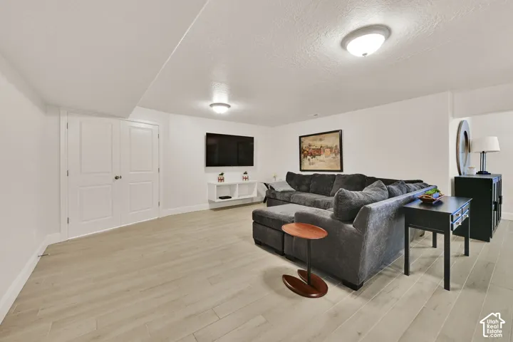 Spacious room featuring light wood-finish flooring, white walls, and recessed lighting