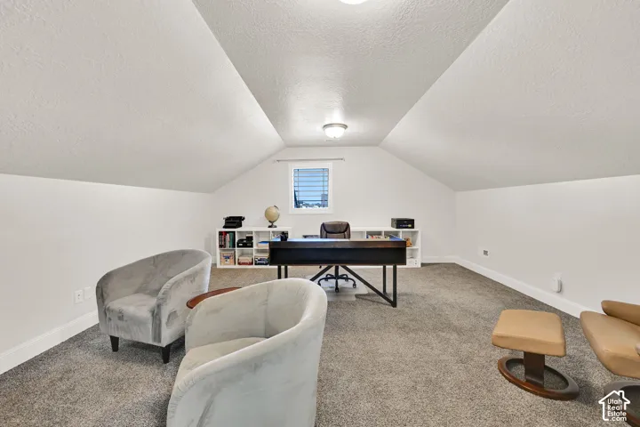 Carpeted room featuring a white ceiling with sloped sections, recessed lighting, and a single window