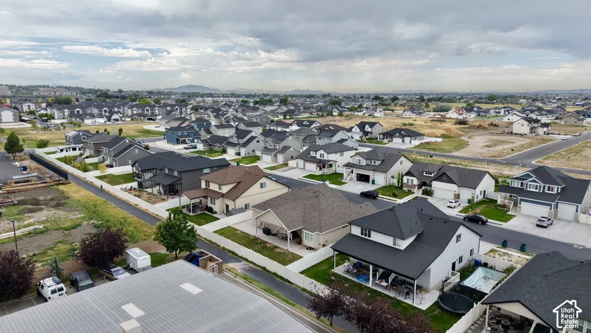 Residential neighborhood featuring a variety of single-family homes with diverse architectural styles, neatly maintained lawns, paved streets, and a mountainous backdrop